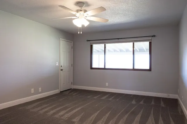 an empty room with a window and a fan