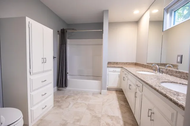 a spacious bathroom with a granite countertop sink mirror and a