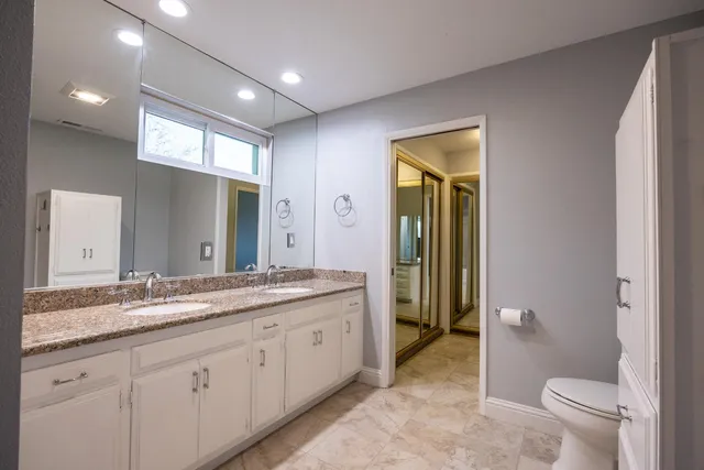 a spacious bathroom with a granite countertop sink mirror and a toilet