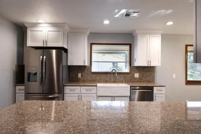 a kitchen with stainless steel appliances kitchen island granite countertop a refrigerator and a stove top oven
