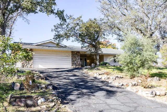 a front view of a house with a yard covered with snow and trees