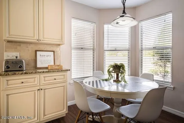 a kitchen with stainless steel appliances granite countertop white cabinets a dining table and chairs