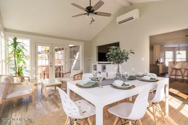 a view of a dining room with furniture a chandelier and large windows