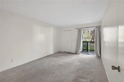 a view of an empty room with window and kitchen view