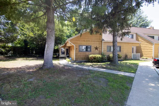 a front view of a house with a yard and large tree