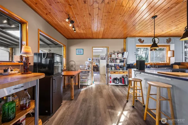 a open kitchen with stainless steel appliances granite countertop a stove refrigerator dining table and chairs with wooden floor