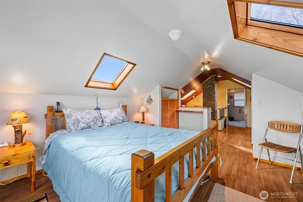 a bedroom with a bed a dresser and wooden floor