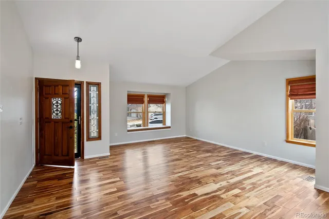 a view of an empty room with window and wooden floor