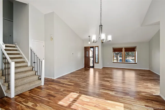 a view of a hallway with wooden floor and a chandelier
