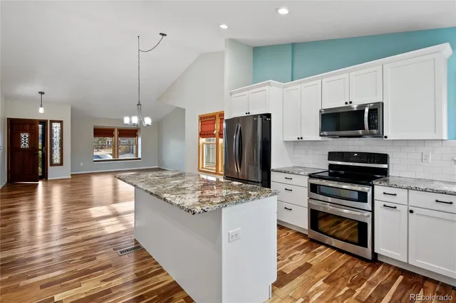 a kitchen with stainless steel appliances kitchen island granite countertop a stove refrigerator and microwave