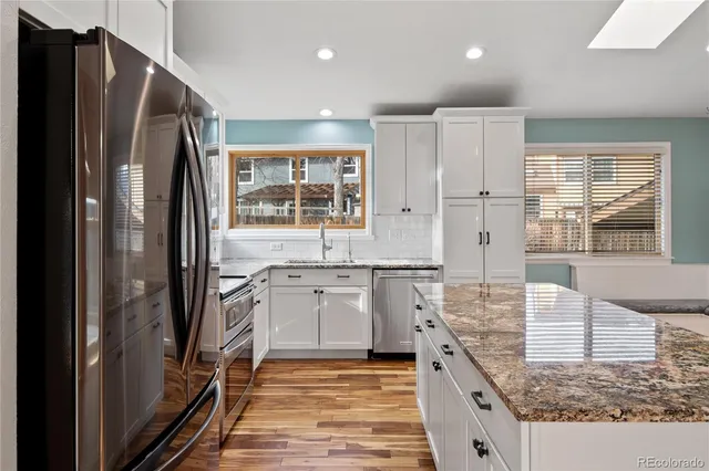 a large kitchen with granite countertop a refrigerator and a sink