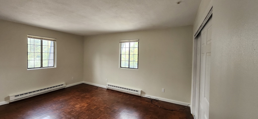 41 West Street, Unit C2 Randolph, MA 02368 - Photo 3 of 12 an empty room with wooden floor and windows