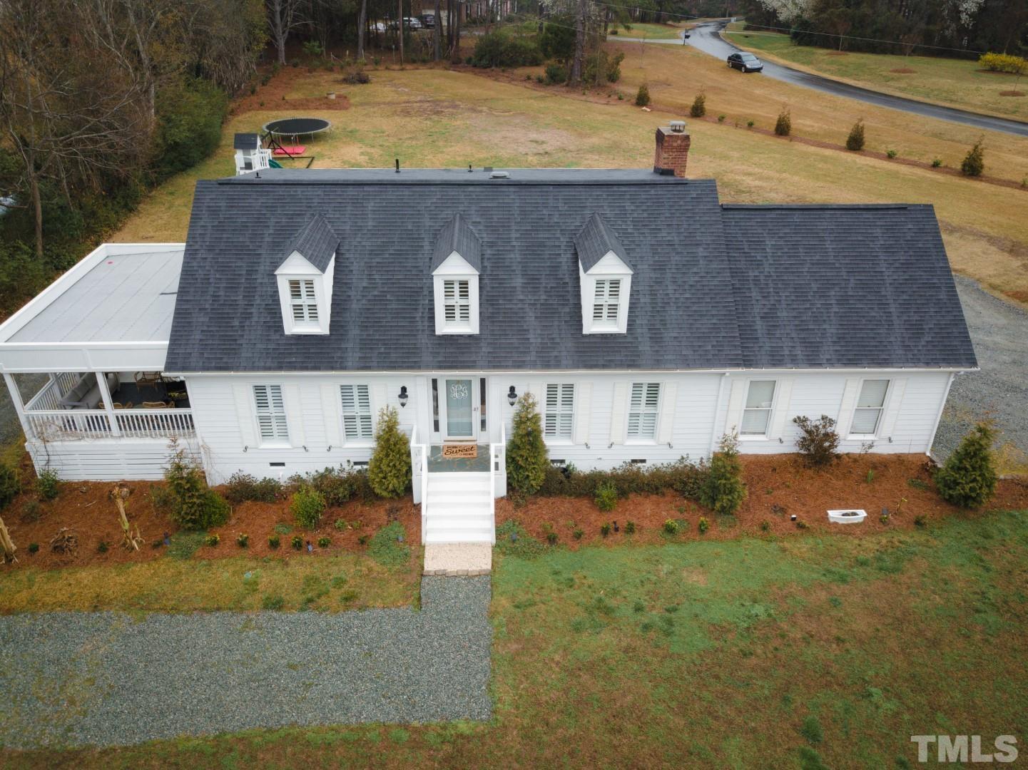 an aerial view of a house with garden space and a car parked on the road