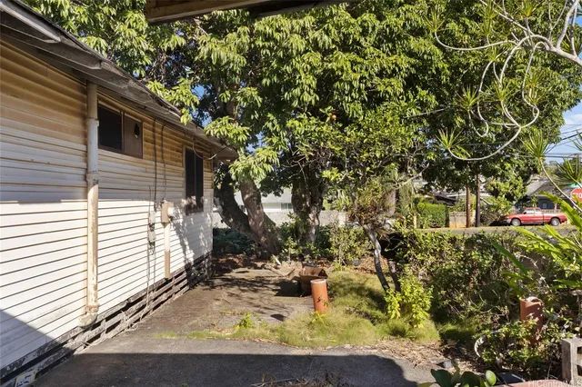a view of a yard with plants and a table and chair