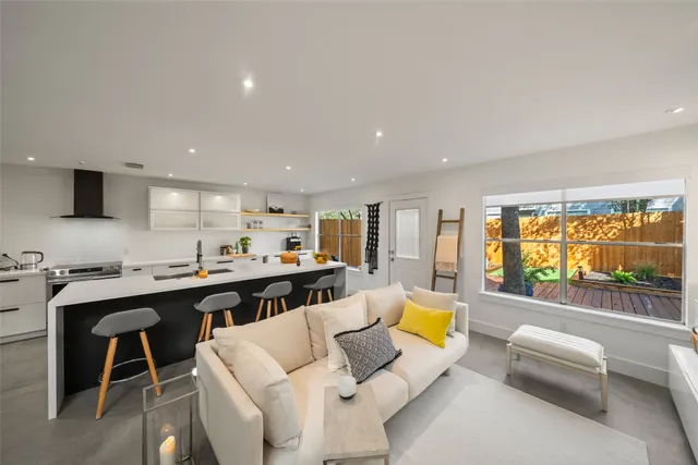 a living room with furniture kitchen view and a large window