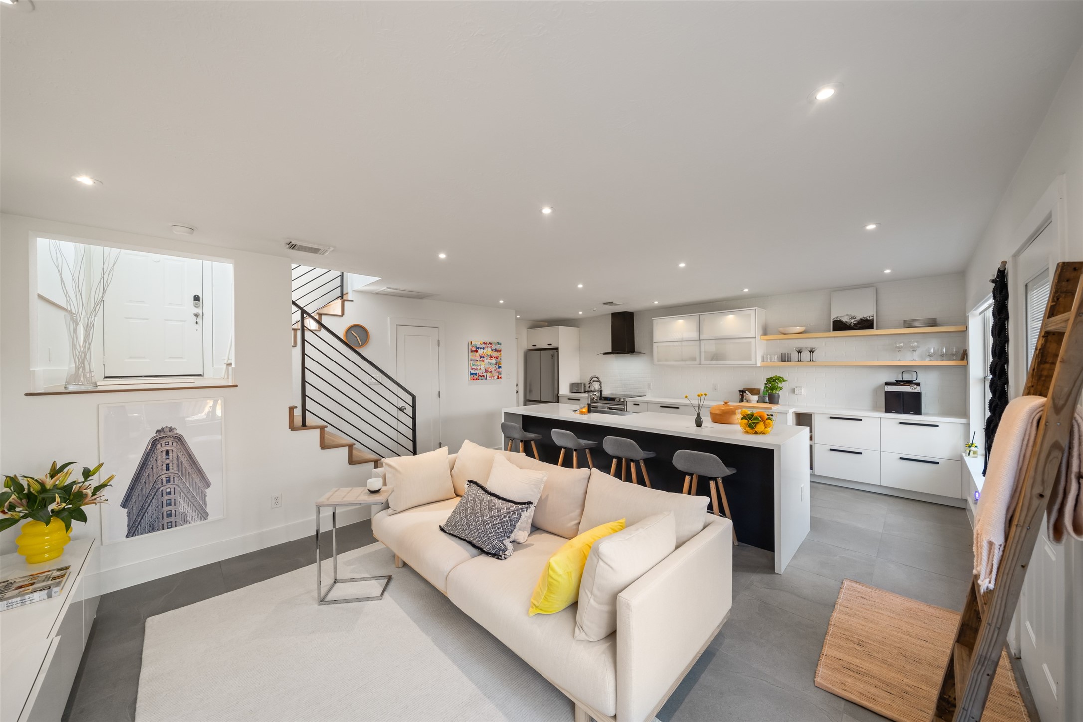 a living room with stainless steel appliances furniture a rug and a kitchen view
