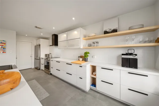 a large white kitchen with stainless steel appliances granite countertop a stove and a sink