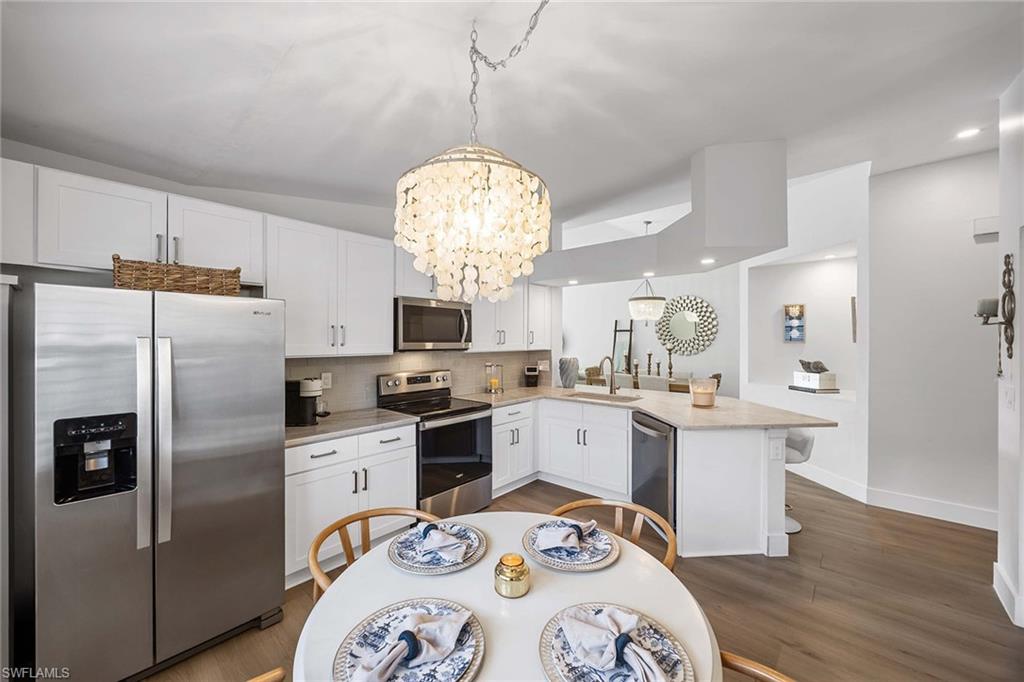2450 Old Groves Road, Unit 201 Naples, FL 34109 - Photo 11 of 32 a kitchen with stainless steel appliances a dining table a sink a stove and refrigerator