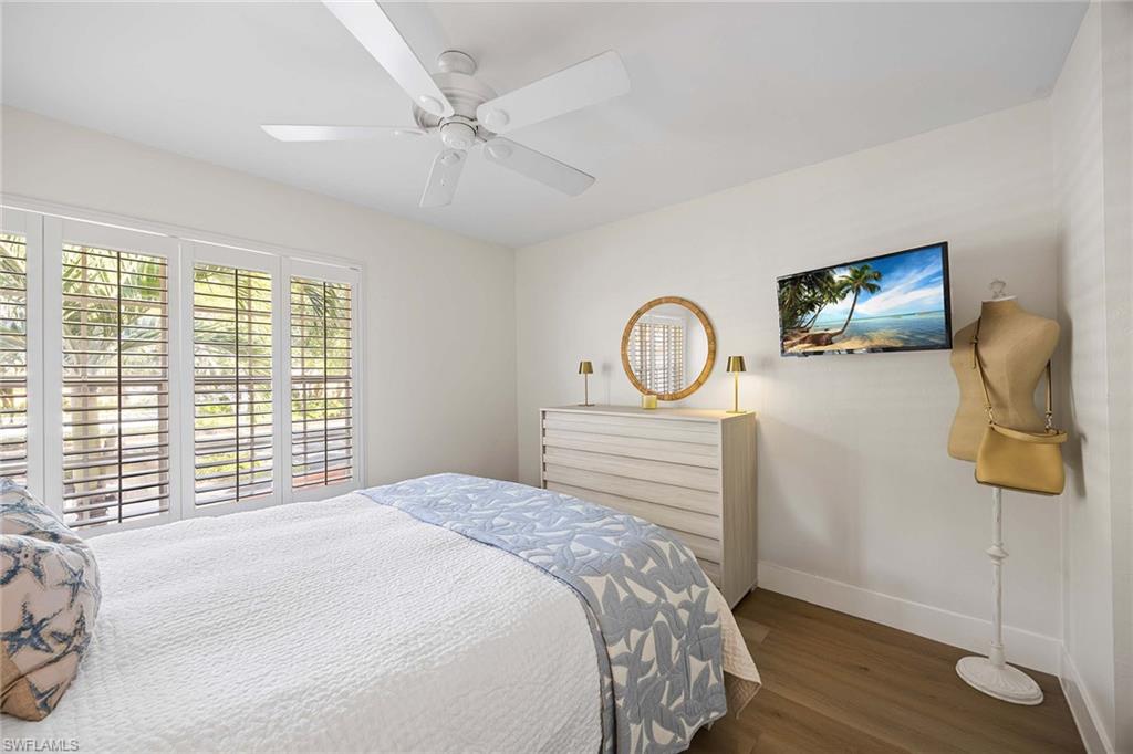 2450 Old Groves Road, Unit 201 Naples, FL 34109 - Photo 21 of 32 a bedroom with a bed and wooden floor
