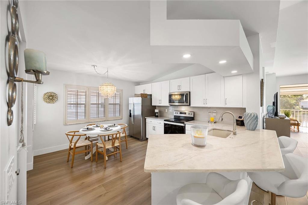 2450 Old Groves Road, Unit 201 Naples, FL 34109 - Photo 9 of 32 a kitchen with stainless steel appliances kitchen island granite countertop a dining table chairs and view living room