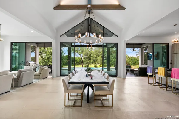 a dining room with furniture a chandelier and a large window