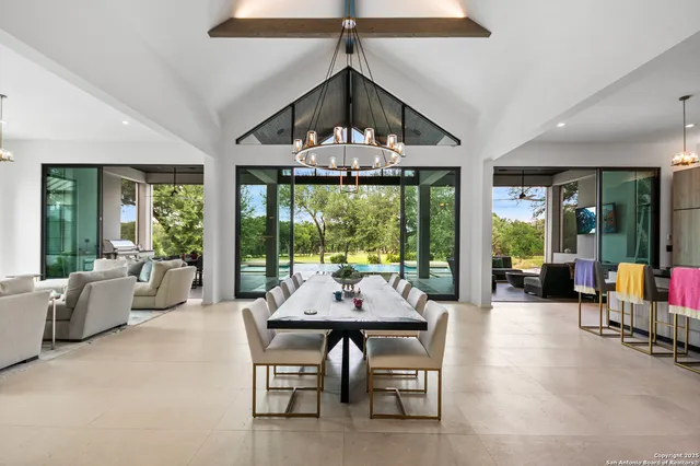 a dining room with furniture a chandelier and a large window
