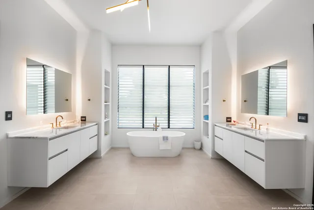 a large bathroom with a double vanity sink a large mirror and a bathtub