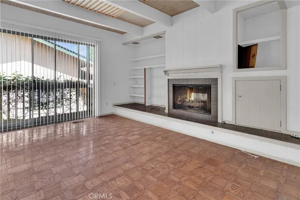 a view of an empty room with a fireplace and a window