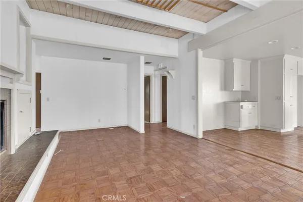 a view of empty room with wooden floor and kitchen