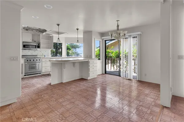 a view of a kitchen with kitchen island a counter top space a sink stainless steel appliances and cabinets