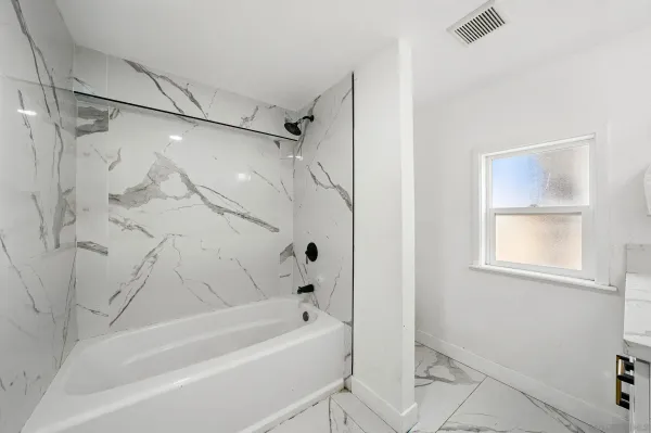 a bathroom with a tub shower vanity and a sink