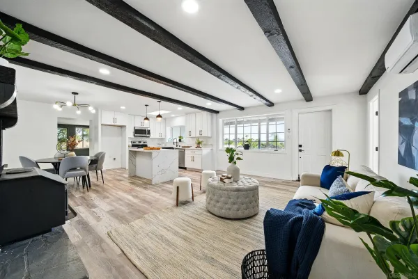 a living room with furniture kitchen view and a chandelier