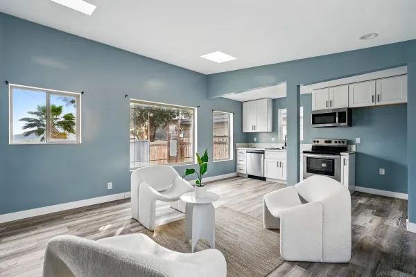 a living room with furniture white walls and kitchen view