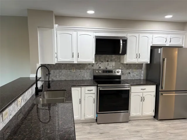 a kitchen with stainless steel appliances granite countertop a stove a microwave and a refrigerator