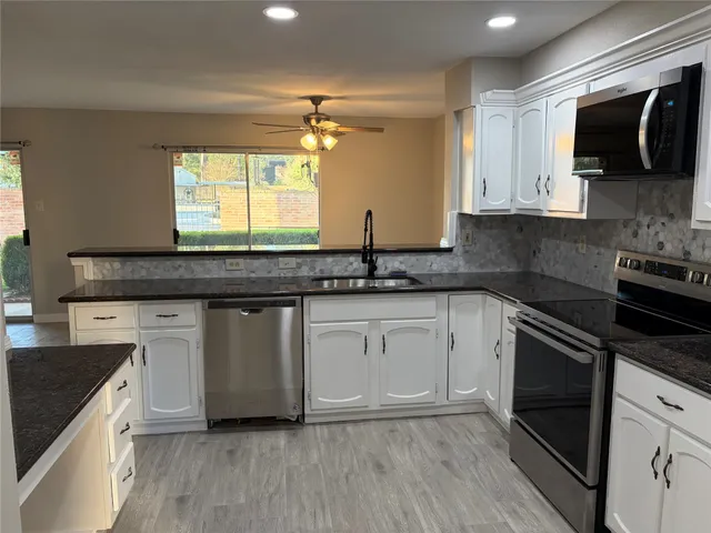 a kitchen with granite countertop a sink and a stove top oven