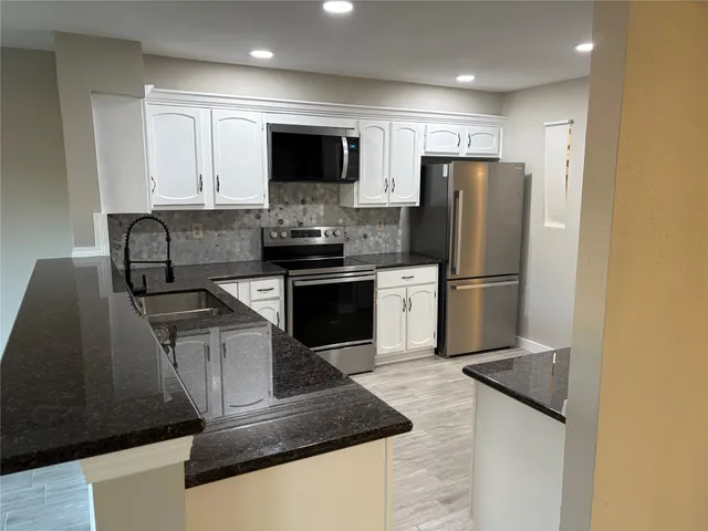 a kitchen with stainless steel appliances granite countertop a refrigerator stove top oven and sink