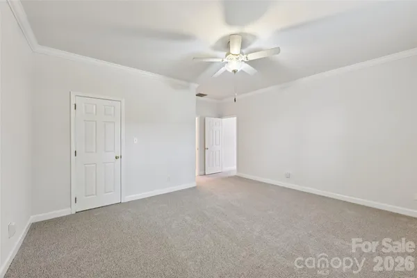an empty room with a chandelier fan and windows