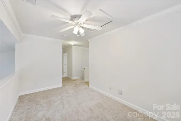 an empty room with a chandelier fan and a bathroom