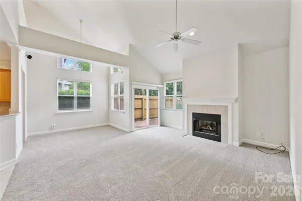 an empty room with windows fireplace and a kitchen view