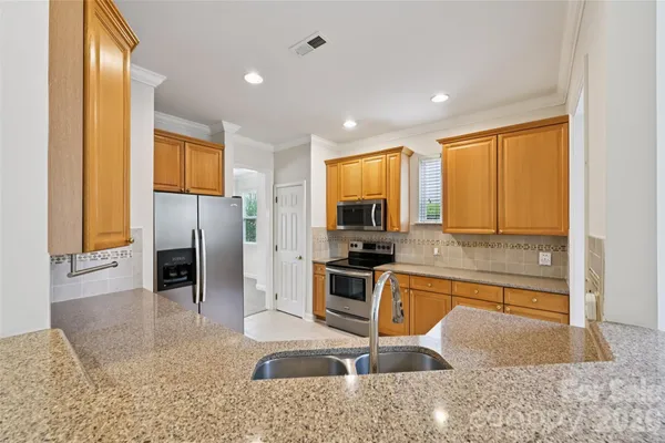 a kitchen with stainless steel appliances granite countertop a refrigerator a stove and a sink with wooden floor