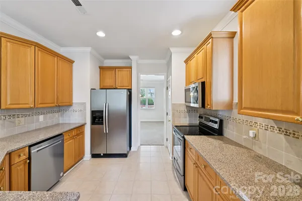 a kitchen with stainless steel appliances granite countertop a refrigerator a stove and a sink with wooden floor