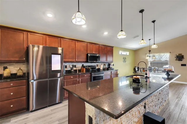 a kitchen with stainless steel appliances granite countertop a sink refrigerator and cabinets
