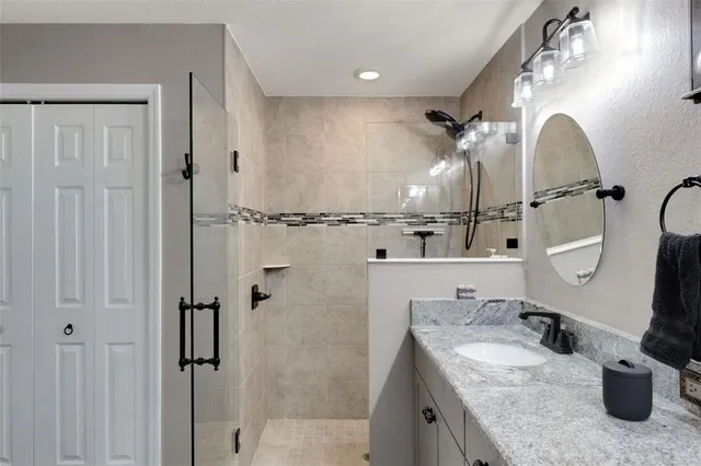 a bathroom with a granite countertop sink a mirror and shower