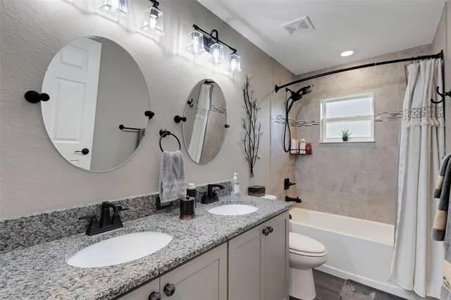 a bathroom with a granite countertop sink mirror toilet and bathtub