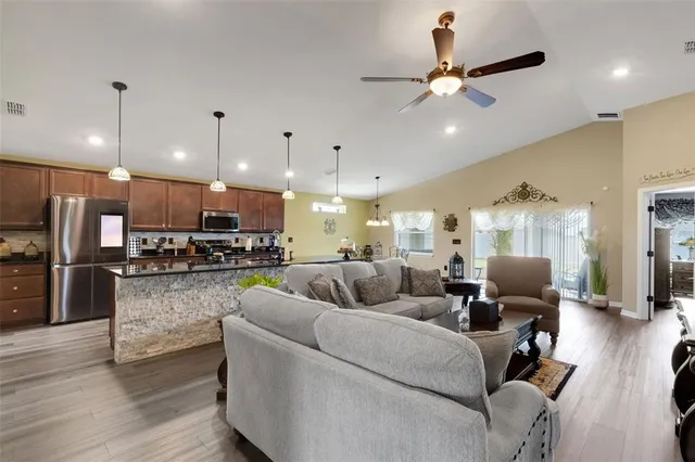 a living room with furniture kitchen area and a chandelier