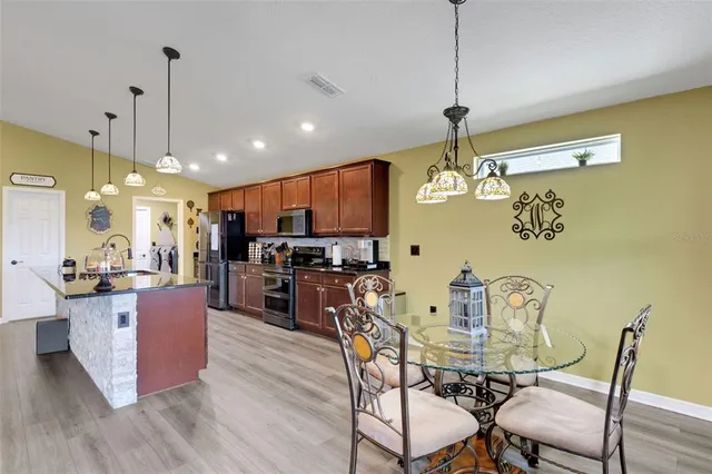a kitchen with stainless steel appliances kitchen island granite countertop a table chairs and a refrigerator