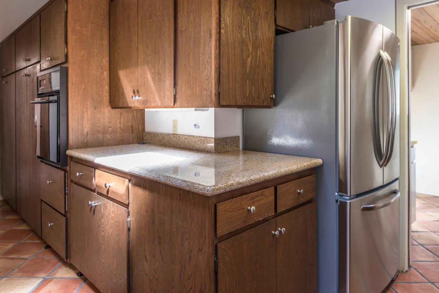 1280 Viscaino Road Pebble Beach, CA 93953 - Photo 35 of 48 a kitchen with stainless steel appliances granite countertop a refrigerator a stove and a sink with wooden cabinets