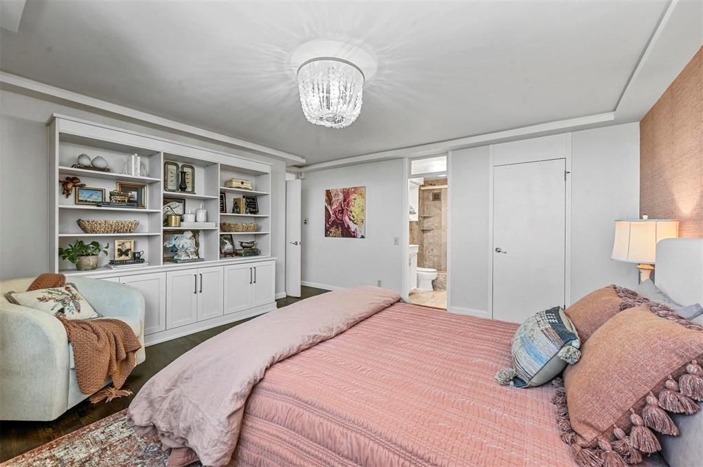 3883 Turtle Creek Boulevard, Unit 2015 Dallas, TX 75219 - Photo 15 of 31 Bedroom featuring wood finished floors and a chandelier