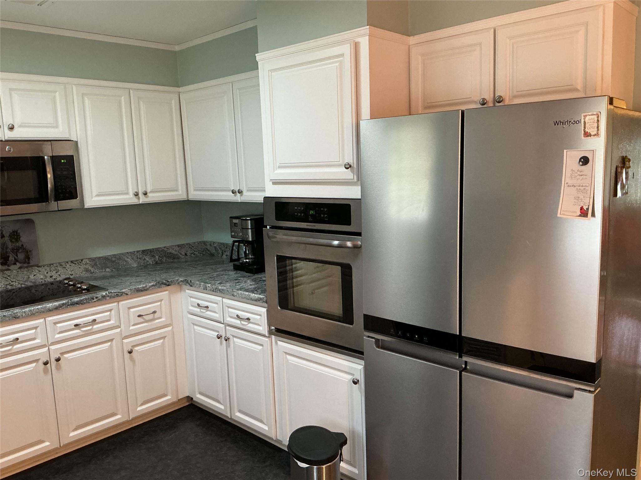207 Woodbridge Drive, Unit B Ridge, NY 11961 - Photo 11 of 22 a kitchen with stainless steel appliances white cabinets and a refrigerator
