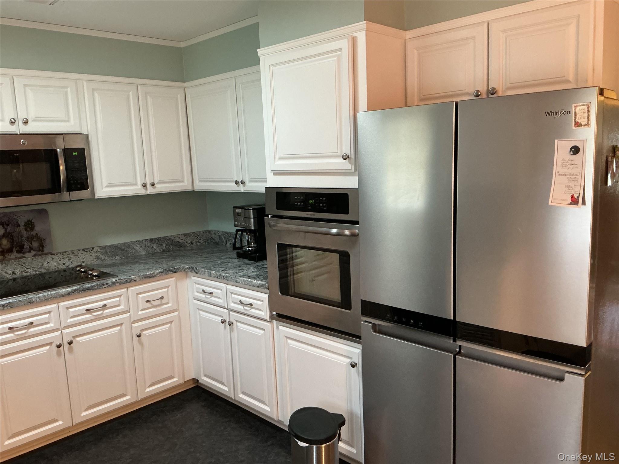 207 Woodbridge Drive, Unit B Ridge, NY 11961 - Photo 12 of 22 a kitchen with cabinets and white stainless steel appliances